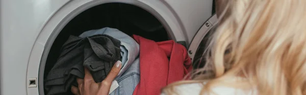 Vista trasera de ama de casa poner la ropa en la lavadora, imagen horizontal - foto de stock