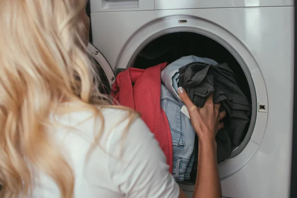 Visão traseira da dona de casa colocando roupa na máquina de lavar roupa — Fotografia de Stock