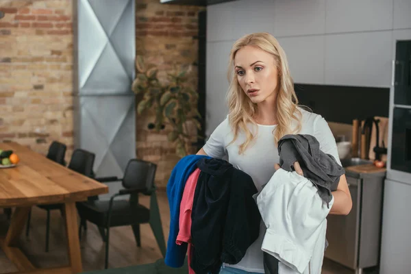 Exhausted housewife standing with hands full of laundry — Stock Photo