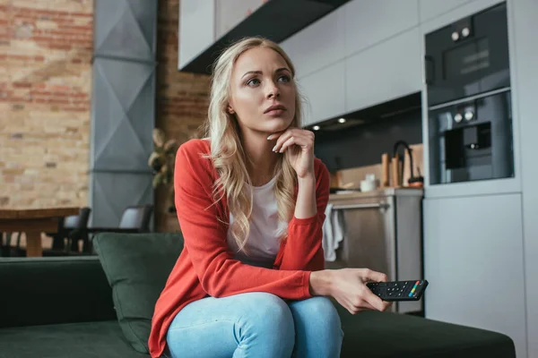 Attentive woman watching tv while sitting on sofa at home — Stock Photo
