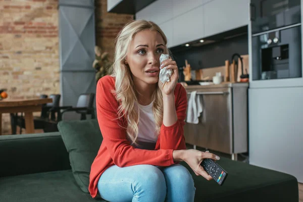 Llorando mujer limpiando lágrimas mientras viendo la televisión en casa - foto de stock