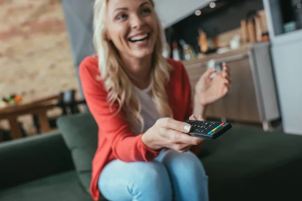 Selective focus of cheerful woman laughing while watching tv at home — Stock Photo