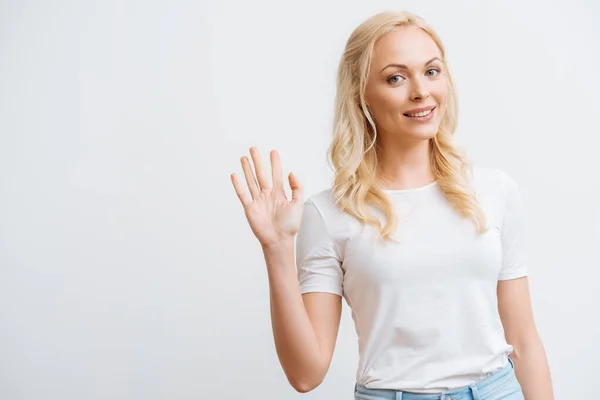 Glückliche schöne Frau winkt mit der Hand, während sie in die Kamera schaut, isoliert auf weiß — Stockfoto
