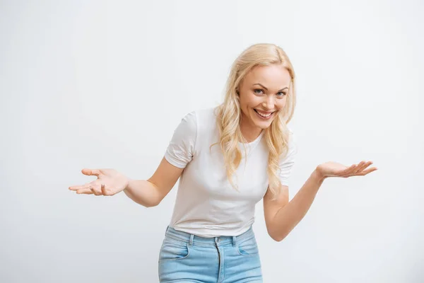 Cheerful blonde woman standing with open arms while smiling at camera isolated on white — Stock Photo