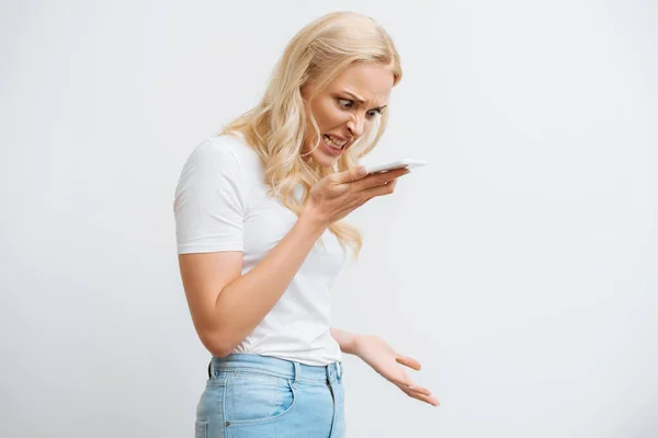 Aggressive girl grimacing during video call on smartphone isolated on white — Stock Photo