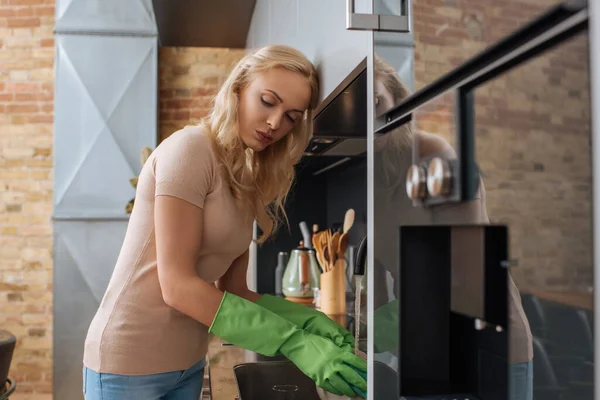 Втомлена домогосподарка в гумових рукавичках миє посуд на кухні — стокове фото
