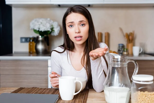 Selective focus of emotional girl gesturing while holding spoon near bowl — Stock Photo