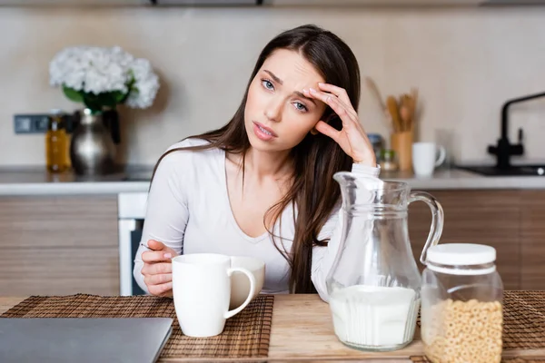Selective focus of upset girl looking at camera while holding spoon near bowl — Stock Photo