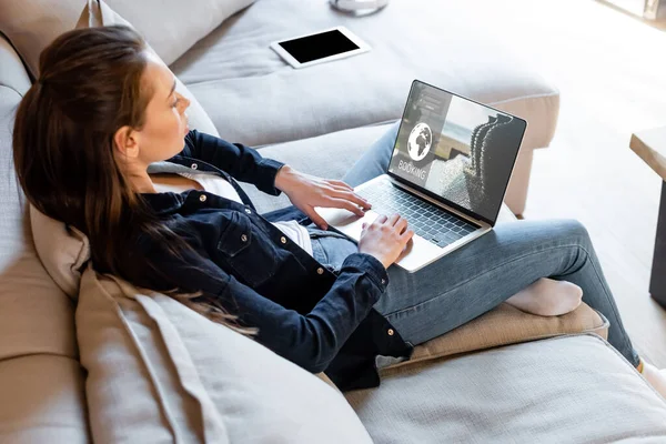 Selective focus of freelancer using laptop with booking website near digital tablet with blank screen — Stock Photo