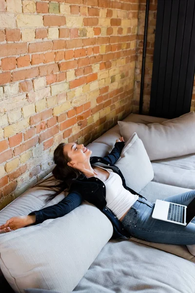 Freelancer alegre com olhos fechados relaxando no sofá com laptop — Fotografia de Stock