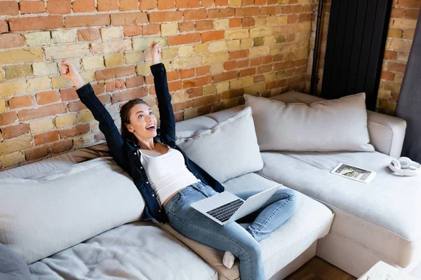 Excited freelancer with hands above head near laptop and digital tablet with  tickets app — Stock Photo