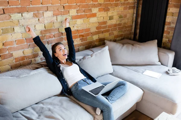 Excited freelancer with hands above head near laptop and digital tablet with white screen — Stock Photo
