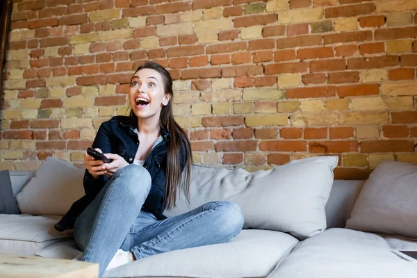 Молодая возбужденная женщина сидит на диване и смотрит кино — стоковое фото
