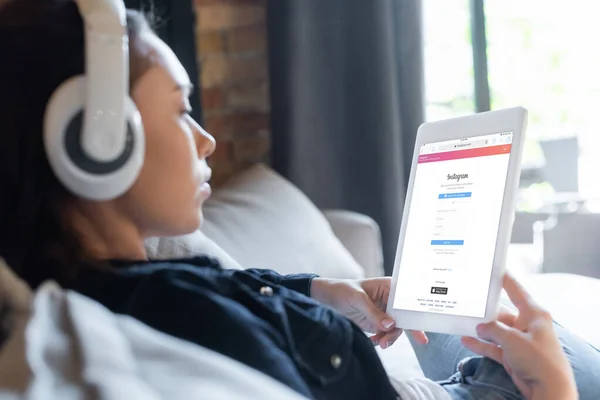 KYIV, UKRAINE - APRIL 29, 2020: selective focus of girl in wireless headphones listening music and using digital tablet with instagram app — Stock Photo