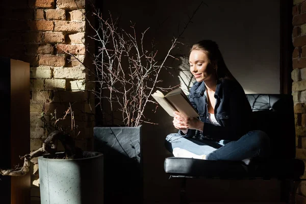 Sonnenlicht auf fröhliche junge Frau, die Buch liest — Stockfoto