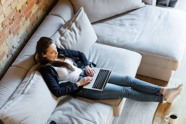 Vista aerea di giovane freelance digitando sulla tastiera del computer portatile a casa — Foto stock