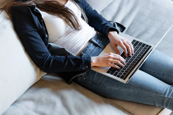 Vista ritagliata di giovane freelance digitando sulla tastiera del computer portatile a casa — Foto stock