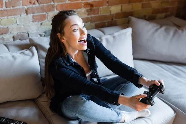 KYIV, UKRAINE - APRIL 29, 2020: excited woman holding joystick while playing video game in living room — Stock Photo