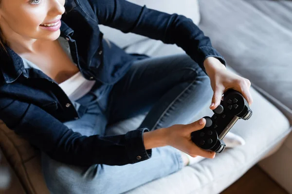 KYIV, UKRAINE - 29 AVRIL 2020 : vue recadrée d'une femme heureuse tenant un joystick tout en jouant à un jeu vidéo dans le salon — Photo de stock