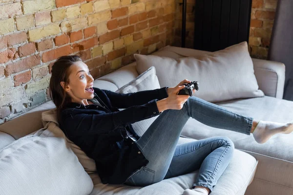 KYIV, UKRAINE - APRIL 29, 2020: cheerful woman holding joystick while playing video game in living room — Stock Photo