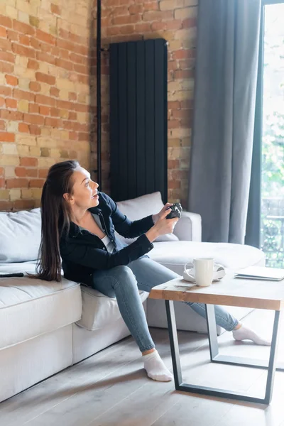 KIEW, UKRAINE - 29. April 2020: Glückliche junge Frau am Steuerknüppel beim Videospiel im Wohnzimmer — Stockfoto