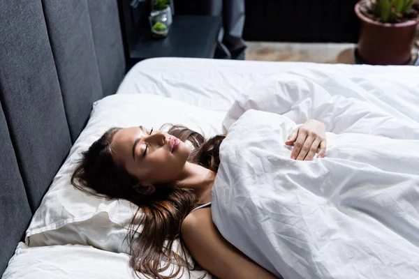 Молодая женщина спит в постели под одеялом — стоковое фото