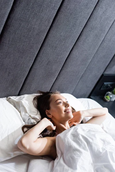 Fröhliche Frau wacht auf und liegt im Bett — Stockfoto