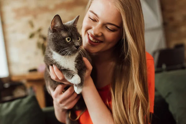 Feliz joven mujer mirando lindo gato en casa - foto de stock