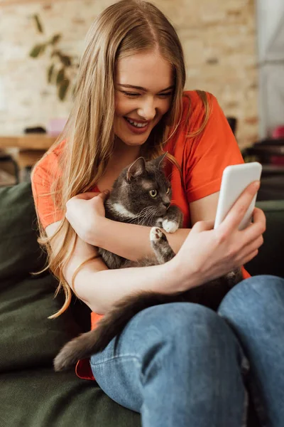 Selective focus of happy young woman taking selfie with cat — Stock Photo