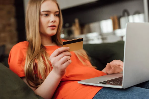 Enfoque selectivo de la mujer joven con tarjeta de crédito cerca de la computadora portátil - foto de stock