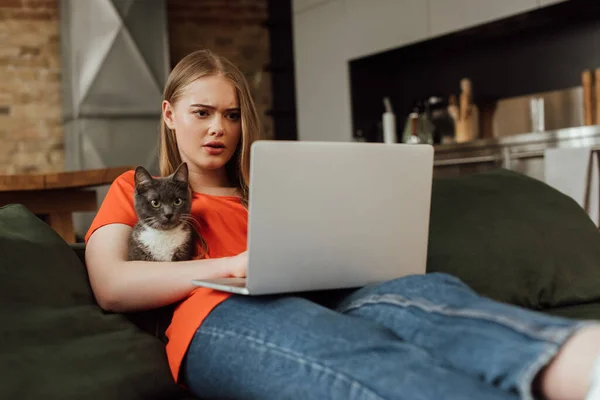 Enfoque selectivo de freelancer atractivo utilizando portátil cerca del gato en la sala de estar — Stock Photo
