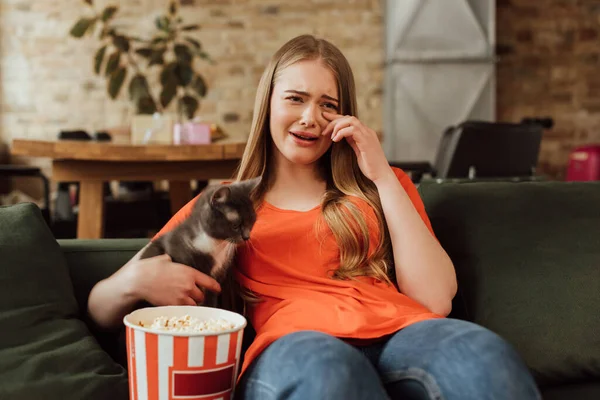 Upset woman crying near cat and popcorn bucket while watching movie — Stock Photo