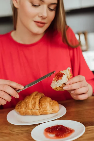 Foco seletivo de mulher atraente segurando faca perto de croissant saboroso com geléia — Fotografia de Stock