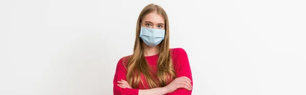 Colheita horizontal de mulher jovem em máscara médica de pé com braços cruzados isolados em branco — Fotografia de Stock