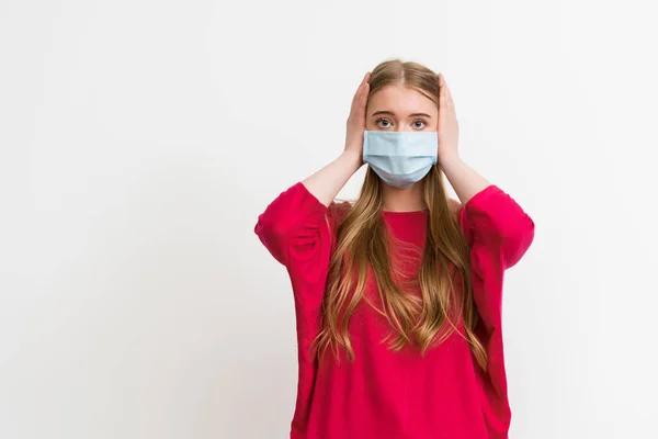 Jovem mulher em máscara médica cobrindo orelhas isoladas em branco — Fotografia de Stock