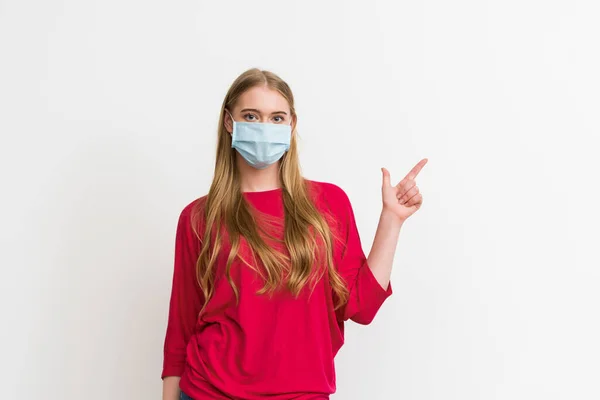 Jeune femme dans le masque médical pointant avec le doigt isolé sur blanc — Photo de stock