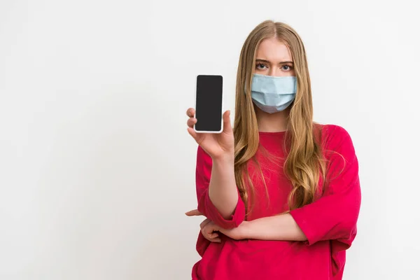 Femme dans le masque médical tenant smartphone avec écran blanc isolé sur blanc — Photo de stock