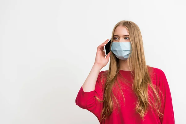 Молода жінка в медичній масці говорить на смартфоні ізольовано на білому — стокове фото