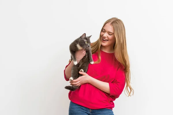 Весела жінка тримає в руках пухнасту кішку ізольовано на білому — стокове фото
