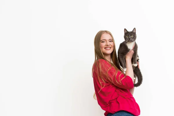 Щаслива молода жінка тримає в руках пухнастий кіт і дивиться на камеру ізольовано на білому — стокове фото