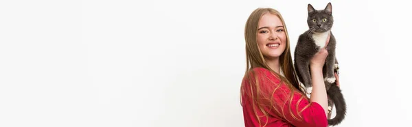 Panoramic shot of happy young woman holding in arms fluffy cat and looking at camera isolated on white — Stock Photo