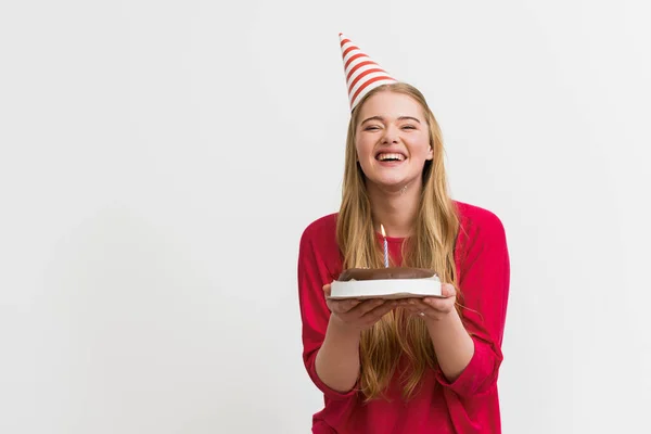 Alegre chica en partido gorra sonriendo y celebración cumpleaños pastel aislado en blanco - foto de stock