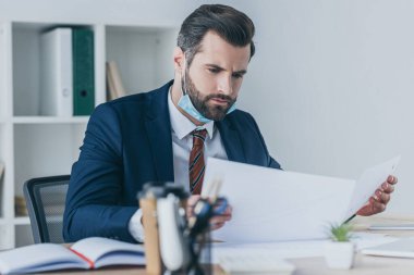 Seçici odaklanma. Ciddi, düşünceli iş adamı. İş yerinde otururken belgelere bakıyor.