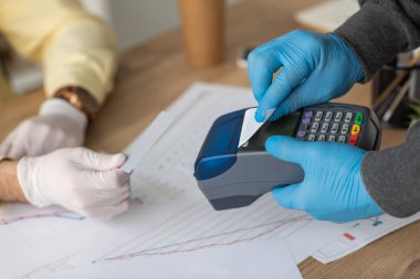 Ödeme terminali ve kredi kartını işadamının yanında tutan teslimatçı görüntüsü. 