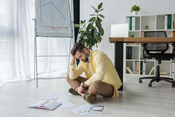 Depressed Businessman Sitting Floor Papers Notebook Flipchart Covid Inscription Graphs — Stock Photo, Image