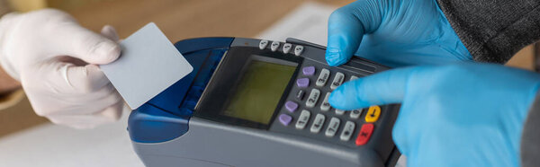 partial view of businessman holding credit card near delivery man with payment terminal, panoramic shot