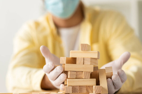 selective focus of businessman in latex gloves near falling wooden blocks tower