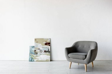 comfortable armchair near paintings in living room  clipart