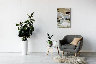 grey armchair near coffee table with green plants and frame in modern living room  clipart