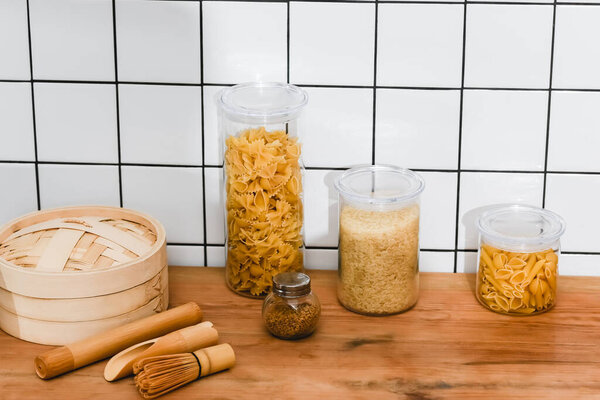 jars with dried pasta and rice near bamboo steamer 